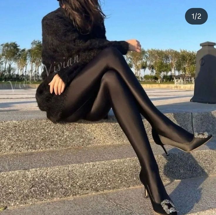 Woman in black leggings and sweater sitting on outdoor steps