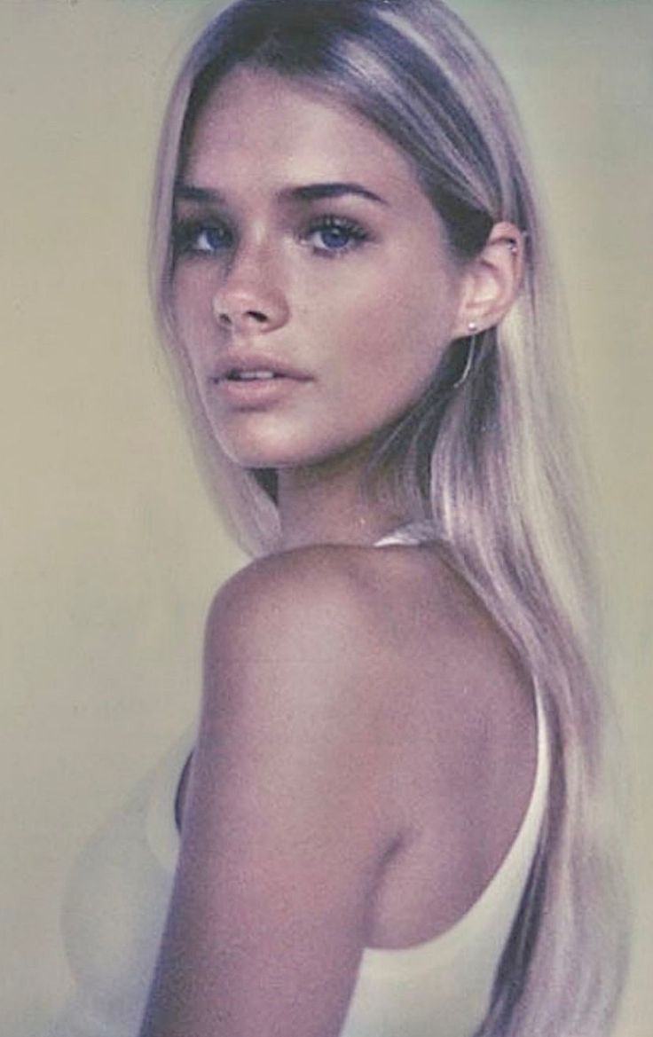 Woman with long blonde hair and blue eyes wearing a white tank top