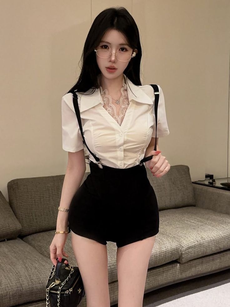 Woman in a white shirt and black shorts with suspenders, holding a small bag