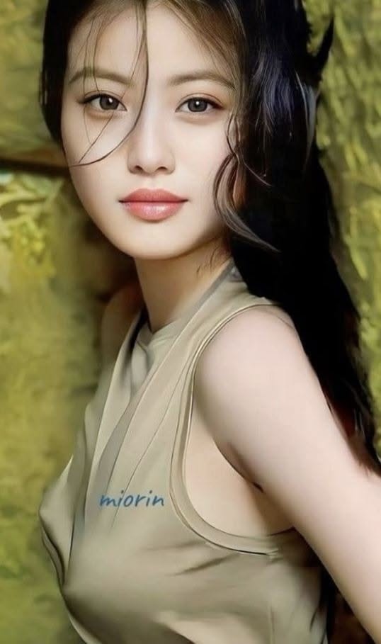 Woman with long dark hair wearing a sleeveless top with text on it
