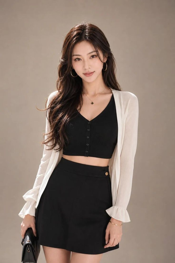 Woman with long hair wearing a black crop top and mini skirt with a white cardigan