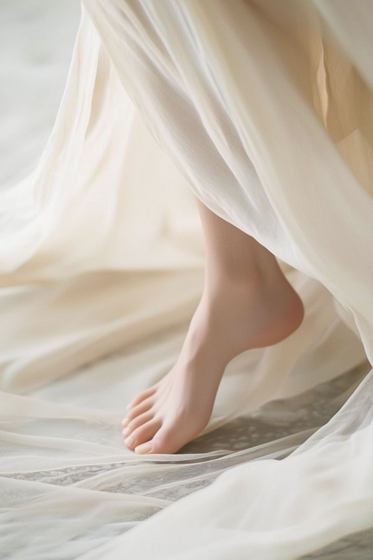 Bare foot stepping on light, flowing fabric with soft lighting