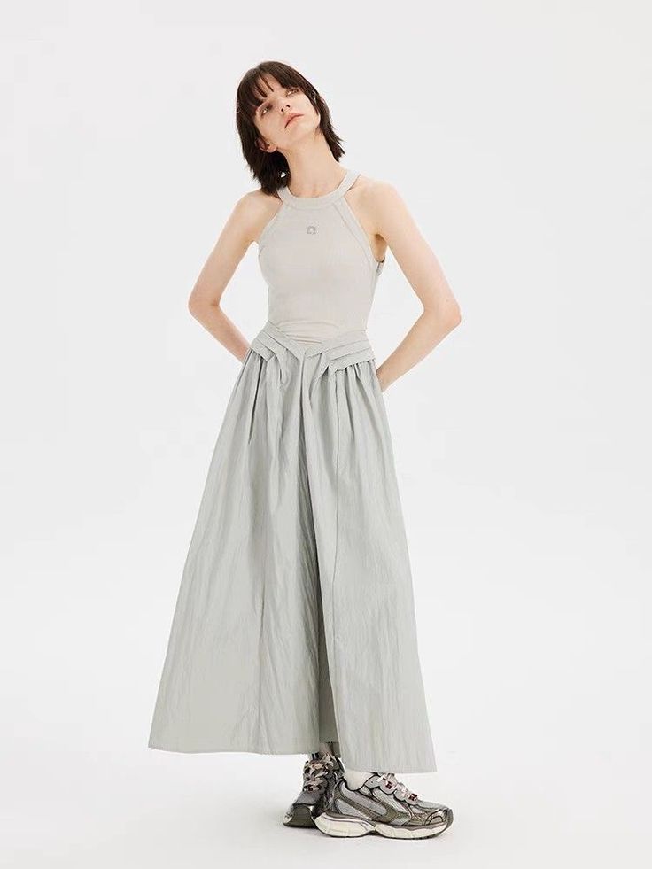 Woman with short hair wearing a sleeveless top and long skirt with sneakers