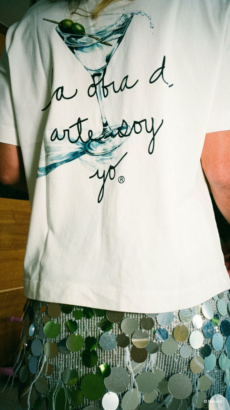 Person wearing a white t-shirt with a martini glass graphic and a sequin skirt