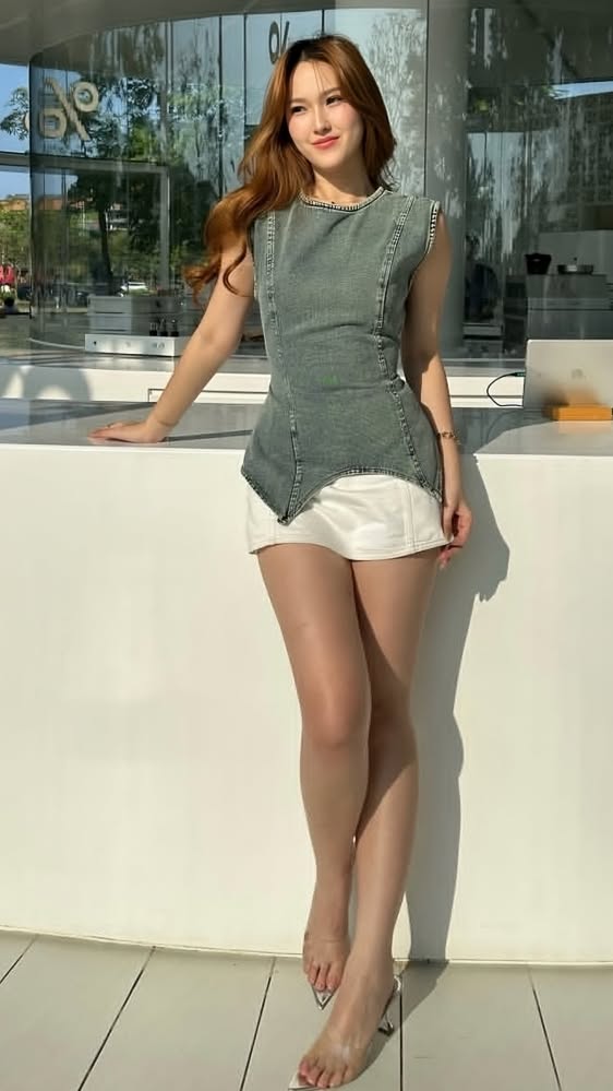 Woman with long hair wearing a denim top and white shorts outdoors