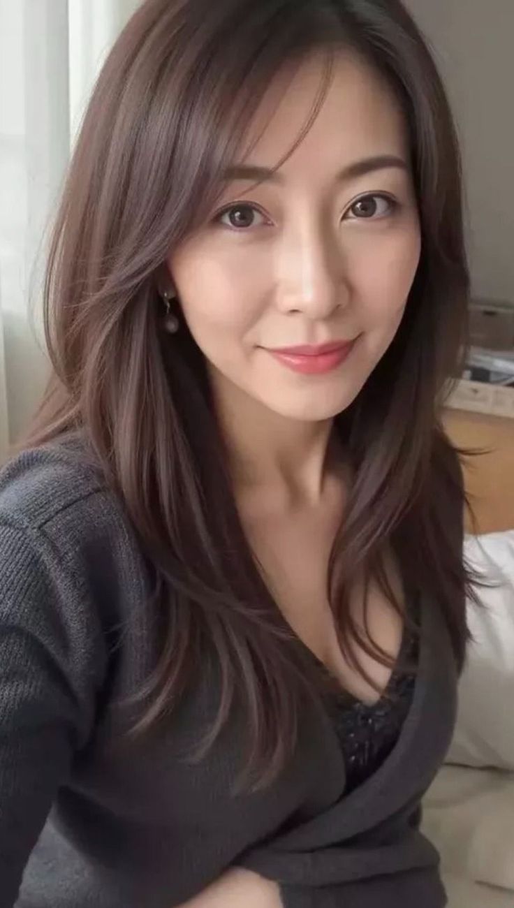 Woman with long dark hair wearing a grey cardigan and showing cleavage