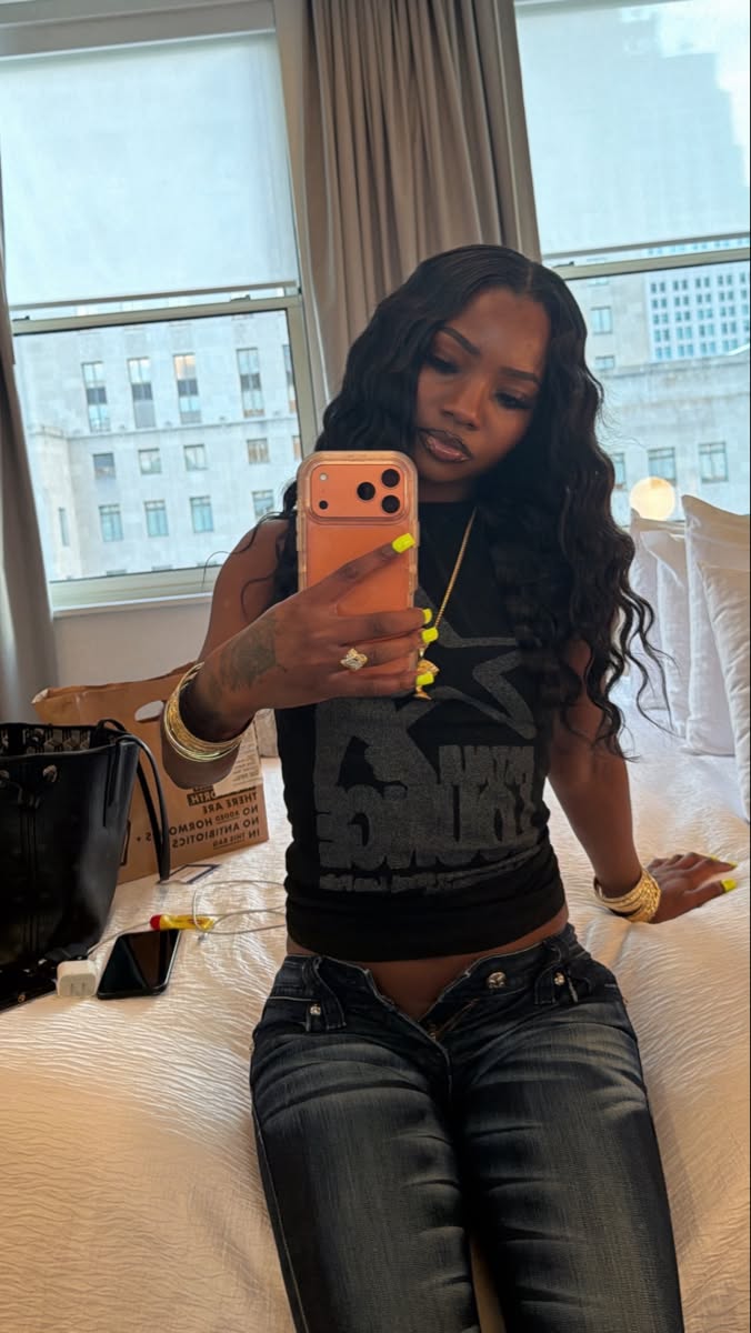 Woman with long black hair taking a selfie in a bedroom