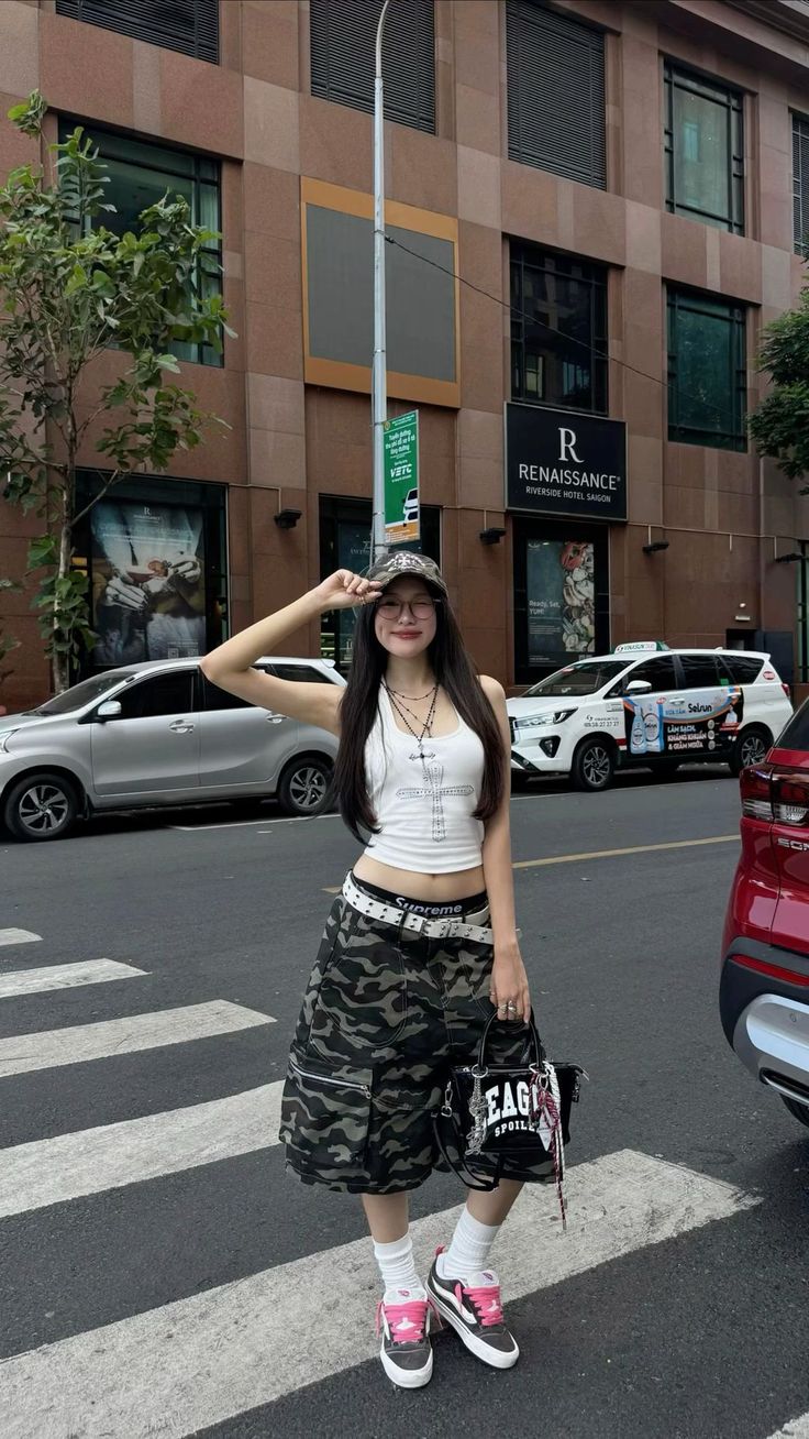 Woman in a crop top and camouflage shorts posing on a city street