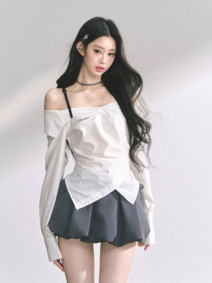 Woman with long black hair wearing an off-shoulder top and pleated skirt