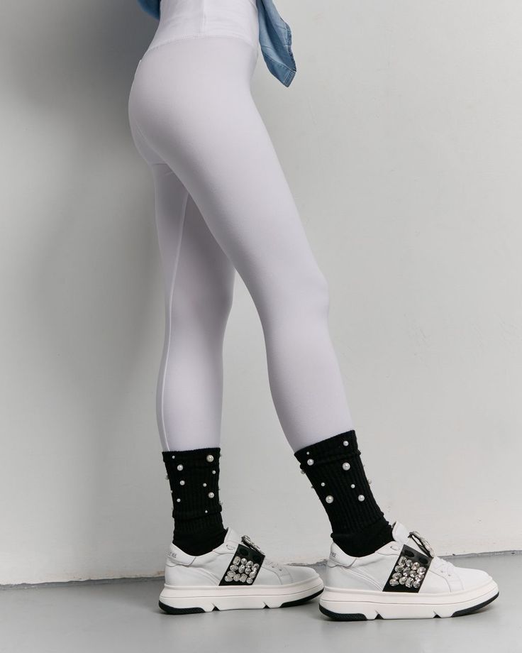 Person wearing white leggings, black pearl-embellished socks, and white sneakers