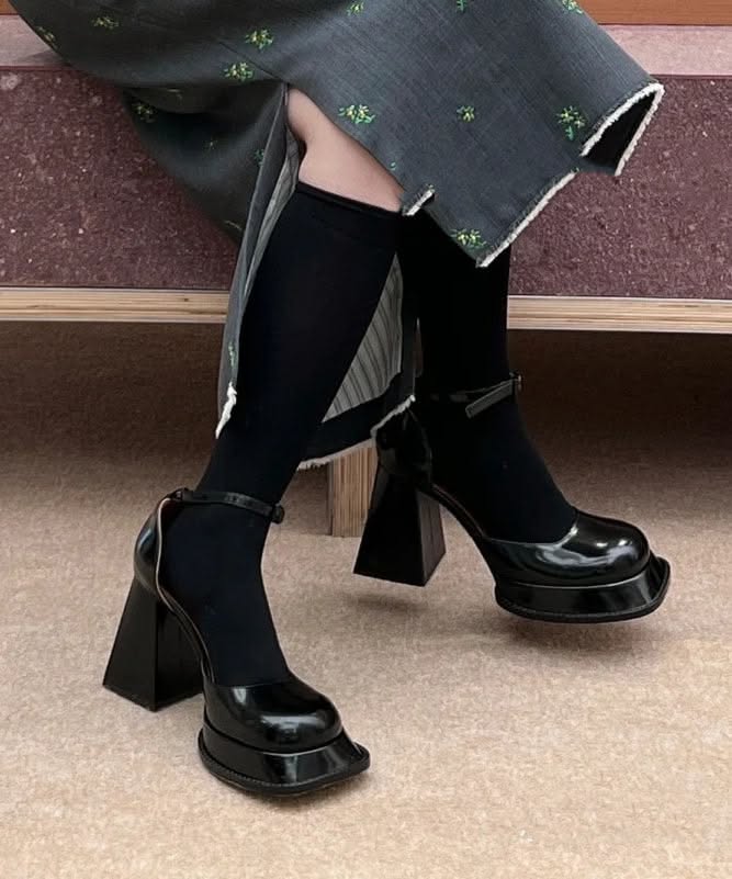 Person wearing black socks and platform mary jane heels with a dark dress