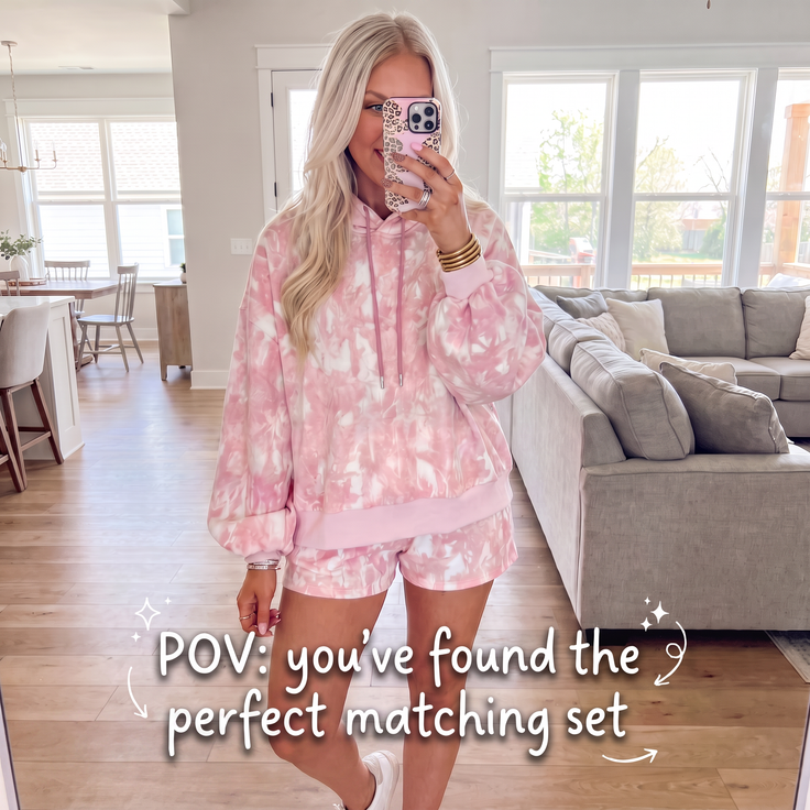 Woman in a pink tie-dye hoodie and matching shorts indoors