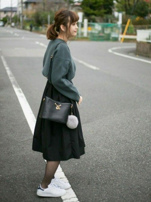 Woman with a ponytail wearing a sweater and black skirt on a street