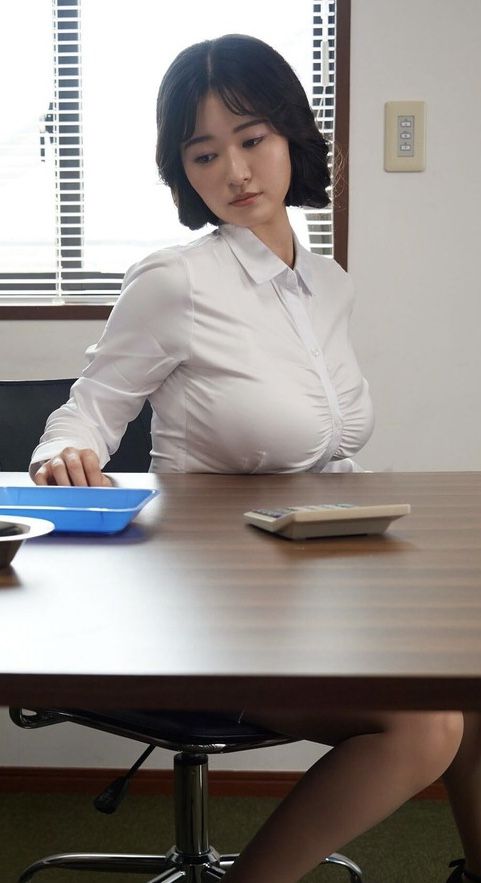 Woman in a white shirt sitting at a desk with a calculator