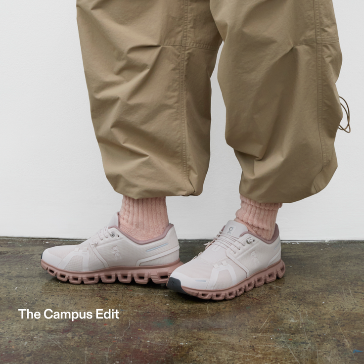 Person wearing pink sneakers, pink socks, and khaki pants on a concrete floor