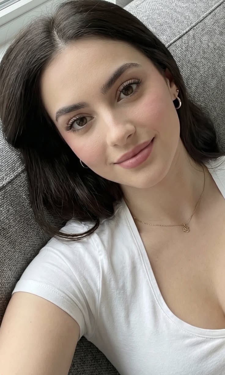 Woman with dark hair wearing a white t-shirt and gold necklace