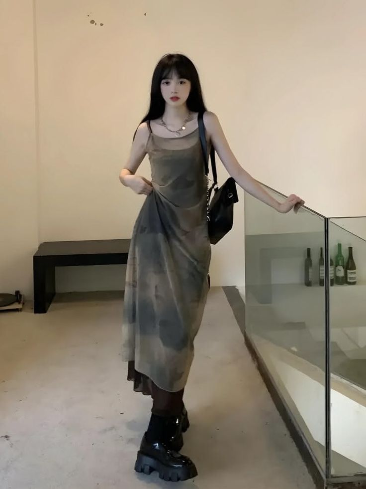 Woman with long black hair wearing a slip dress and chunky shoes indoors