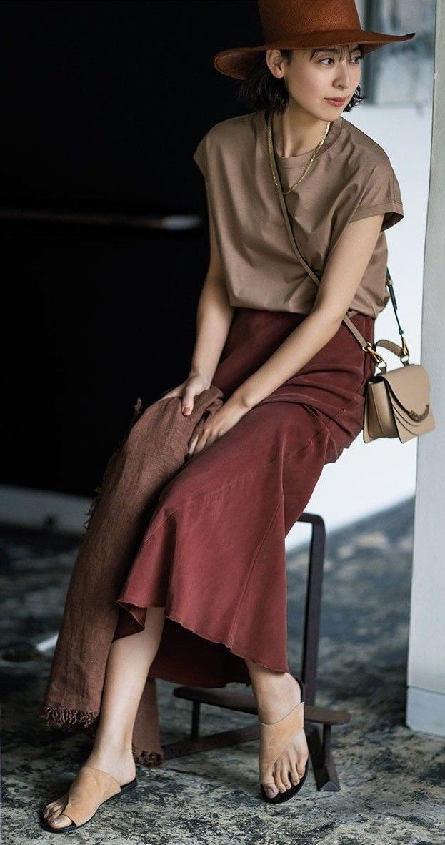 Woman in a brown hat and midi skirt sitting indoors