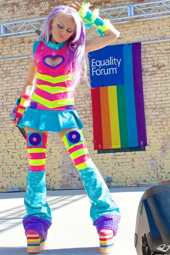 Woman in a vibrant, colorful outfit with rainbow platform shoes standing outdoors