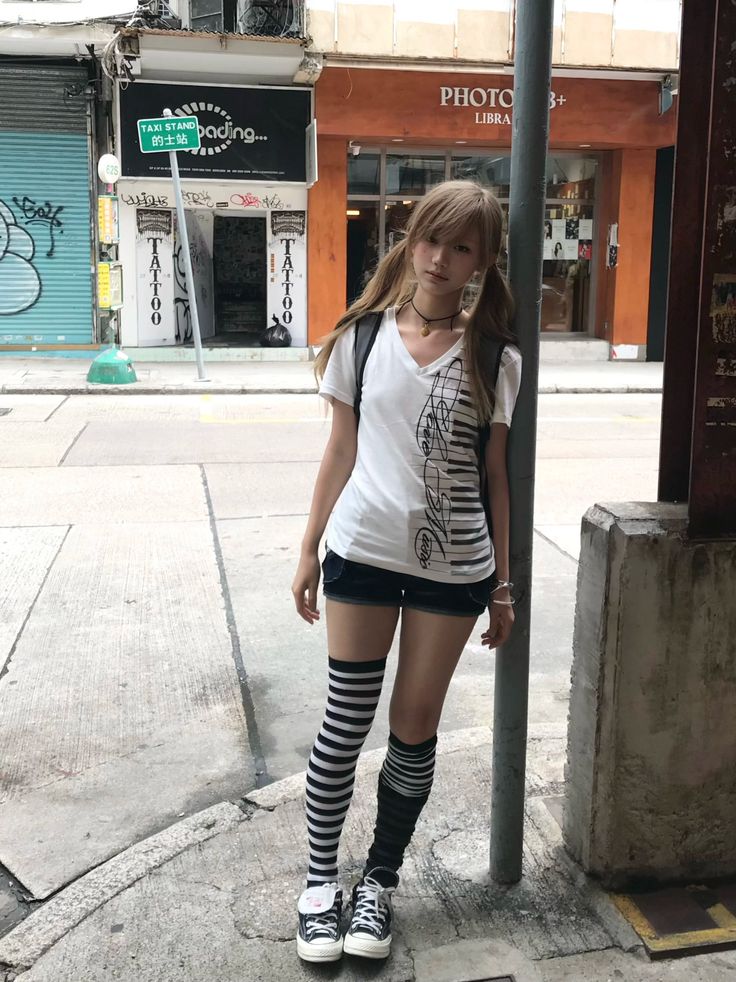 Young woman with pigtails and striped socks standing on a city street
