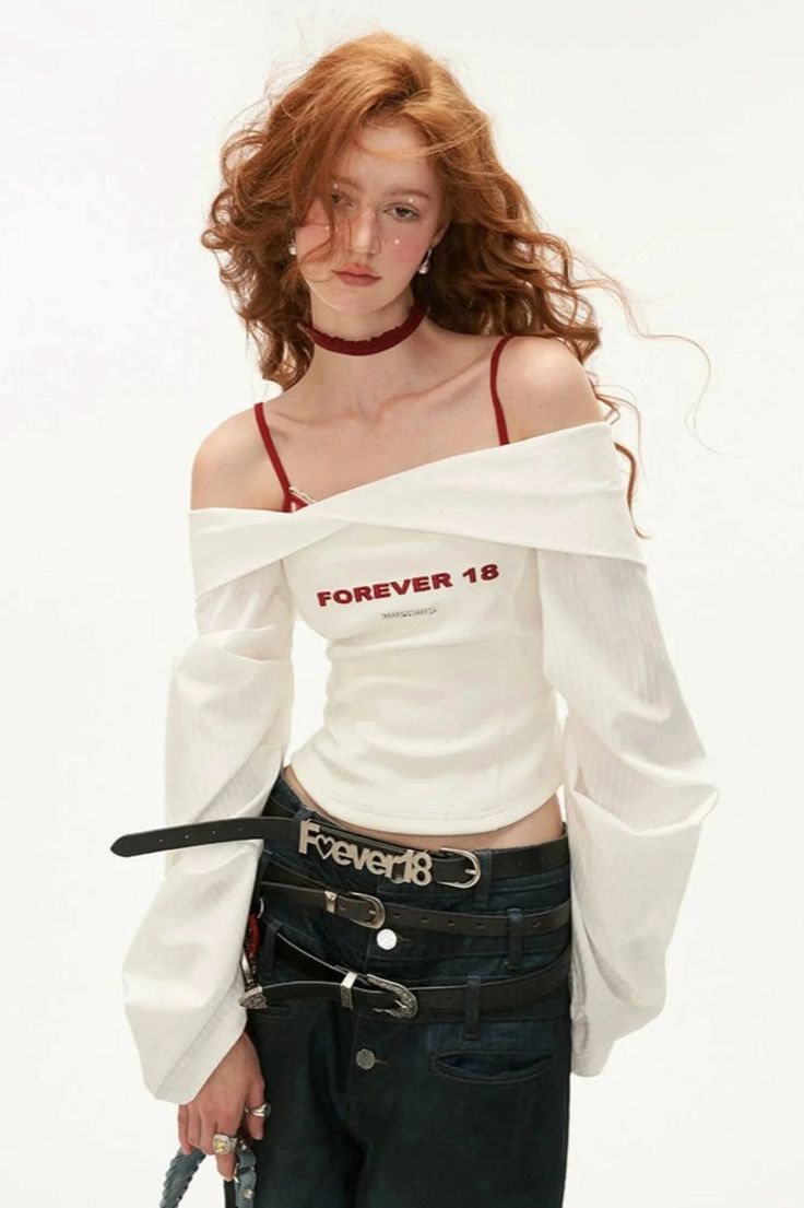 Woman with red hair wearing an off-shoulder top and multiple belts