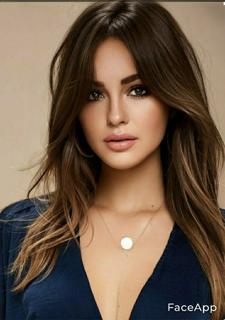 Woman with long brown hair wearing a deep V-neck top and a necklace