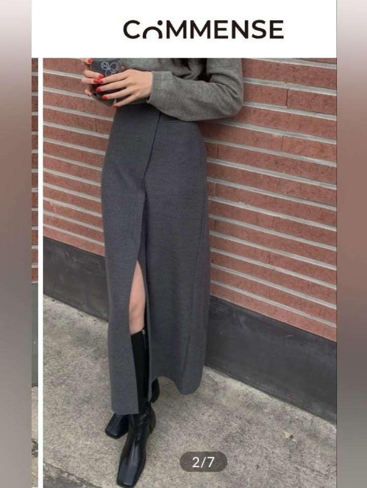 Woman in a gray sweater and long skirt with a high slit, holding a cup