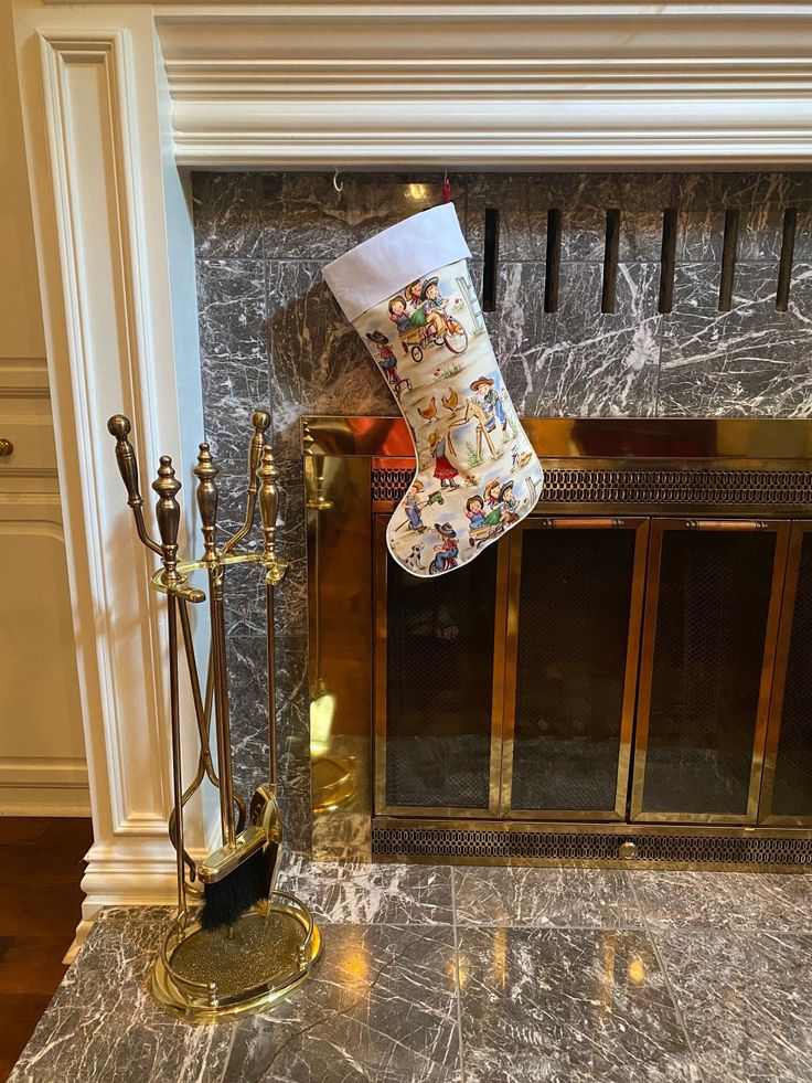 Christmas stocking hanging on a marble fireplace with brass accents and fireplace tools