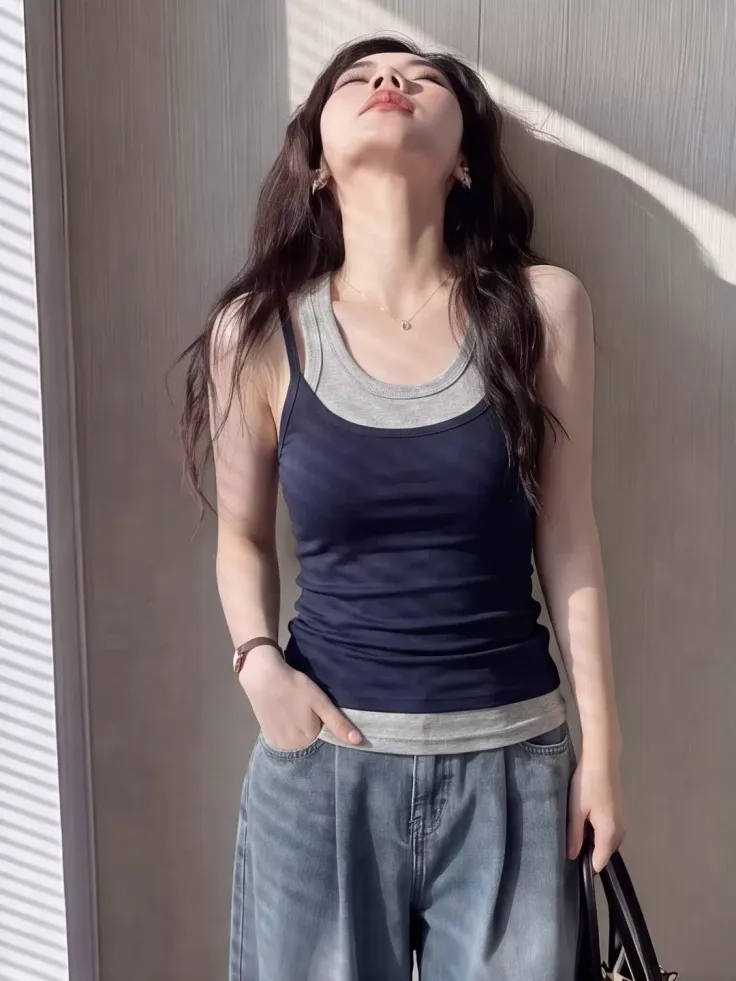 Woman in layered tank tops and wide leg jeans with dramatic lighting