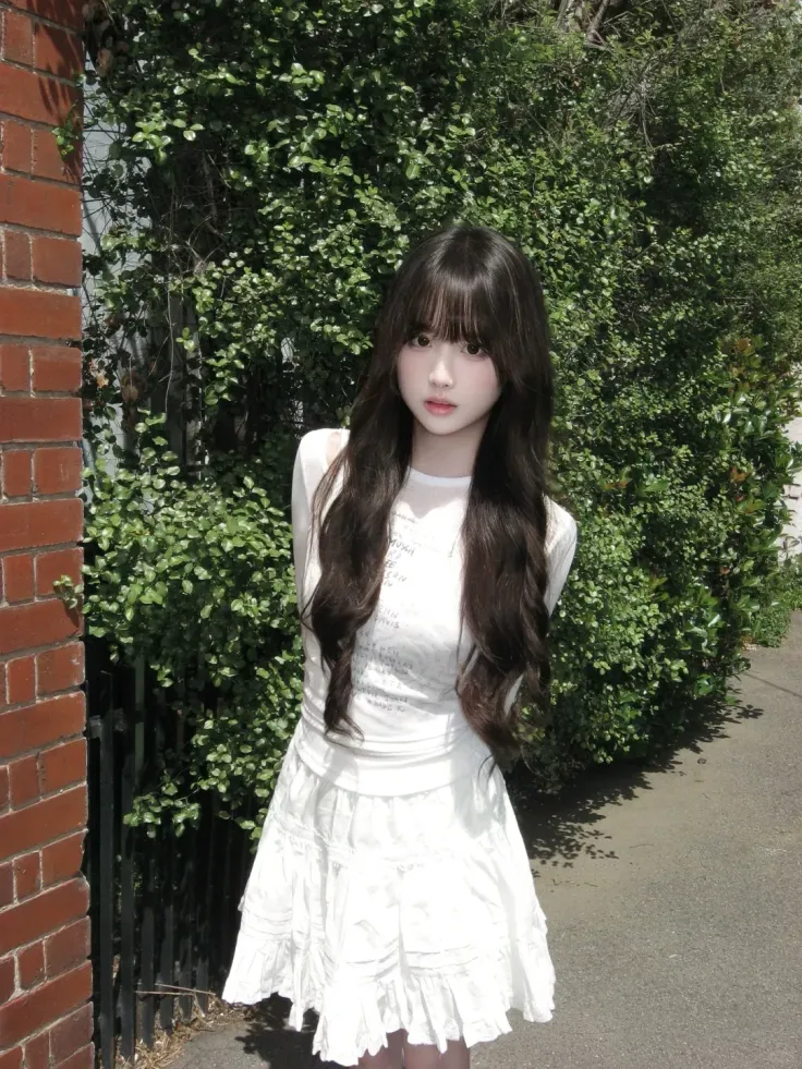Woman with long dark hair in a white dress standing outdoors