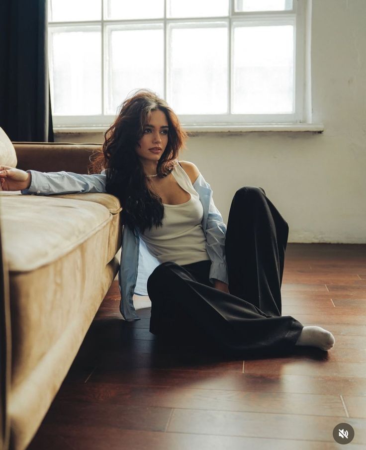 Woman with long hair sitting on the floor next to a couch