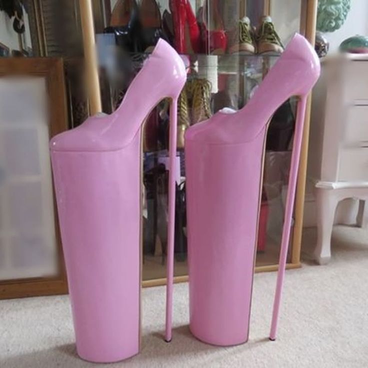 Pair of extremely tall pink platform stiletto heels on a carpeted floor