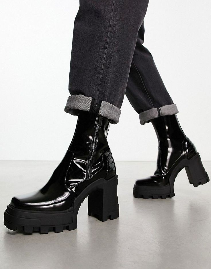 Person wearing black patent leather platform boots and cuffed dark wash jeans