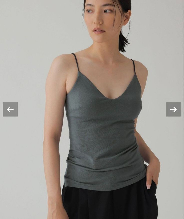 Woman in a gray camisole and black pants in a studio setting