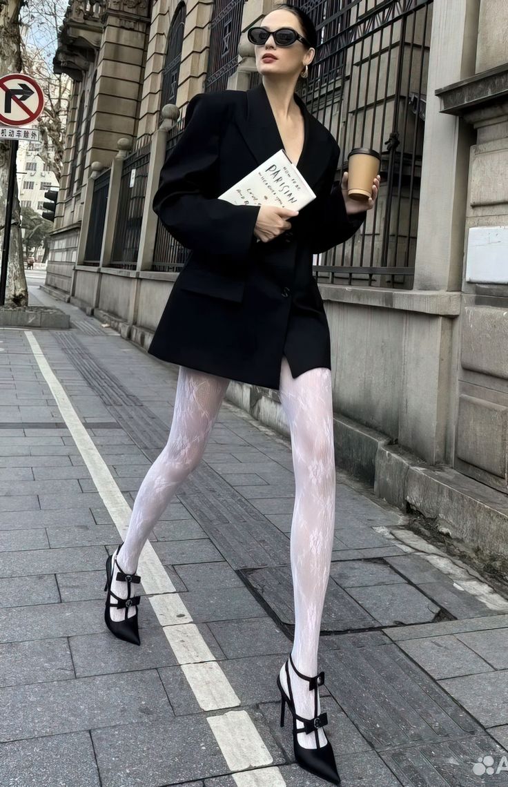 Woman in a black blazer and white patterned tights walking on a street