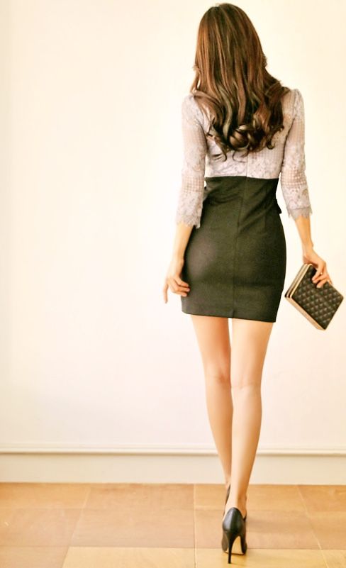 Woman with long hair in a lace top and mini skirt holding a clutch bag