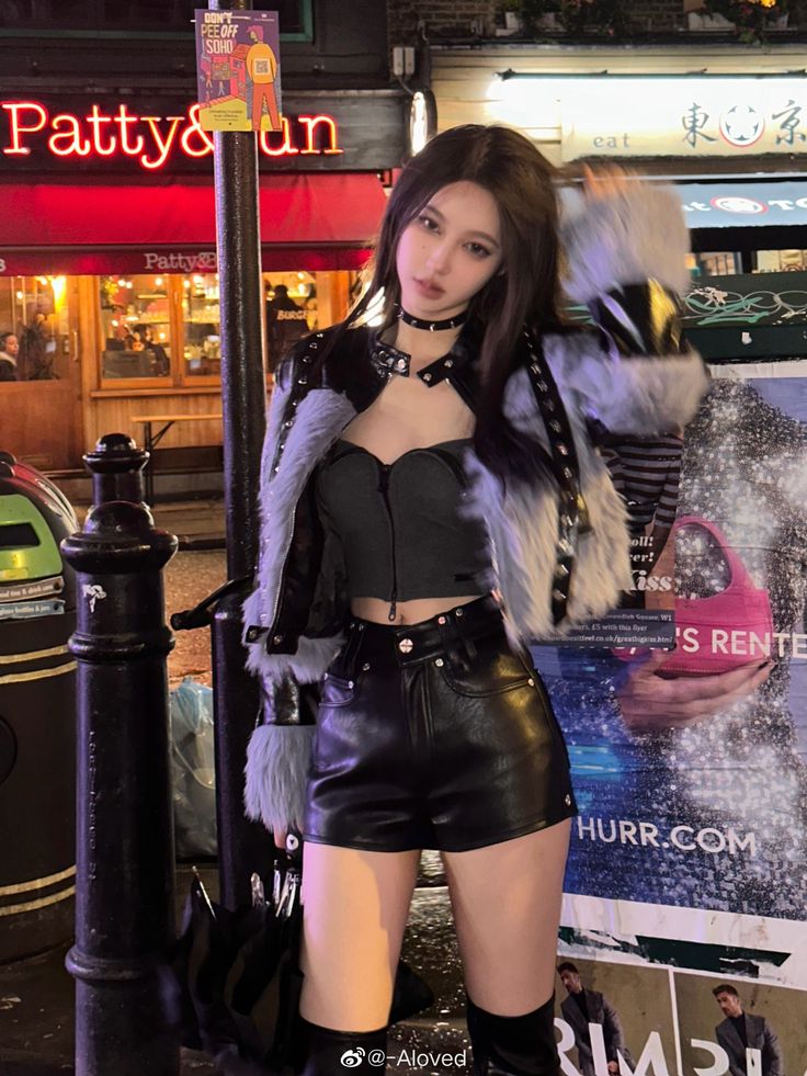 Woman in a leather jacket with fur trim and leather shorts on a street at night