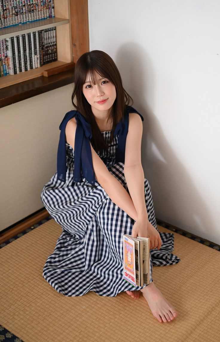 Woman in a gingham dress sitting on a tatami mat with books