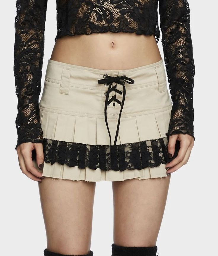 Woman wearing a black lace crop top and a beige pleated mini skirt with lace trim