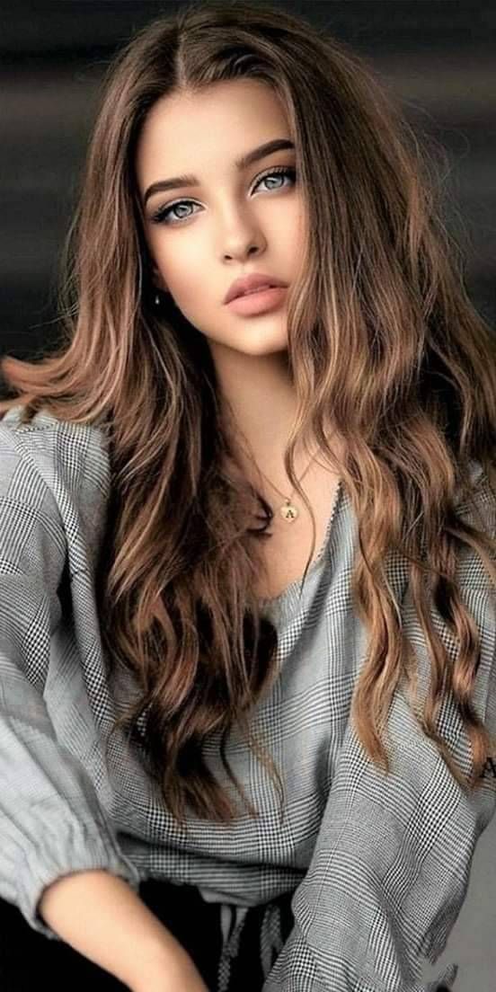 Woman with long brown hair wearing a plaid shirt and a necklace