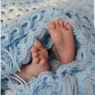 Baby feet peeking out from a blue crochet blanket
