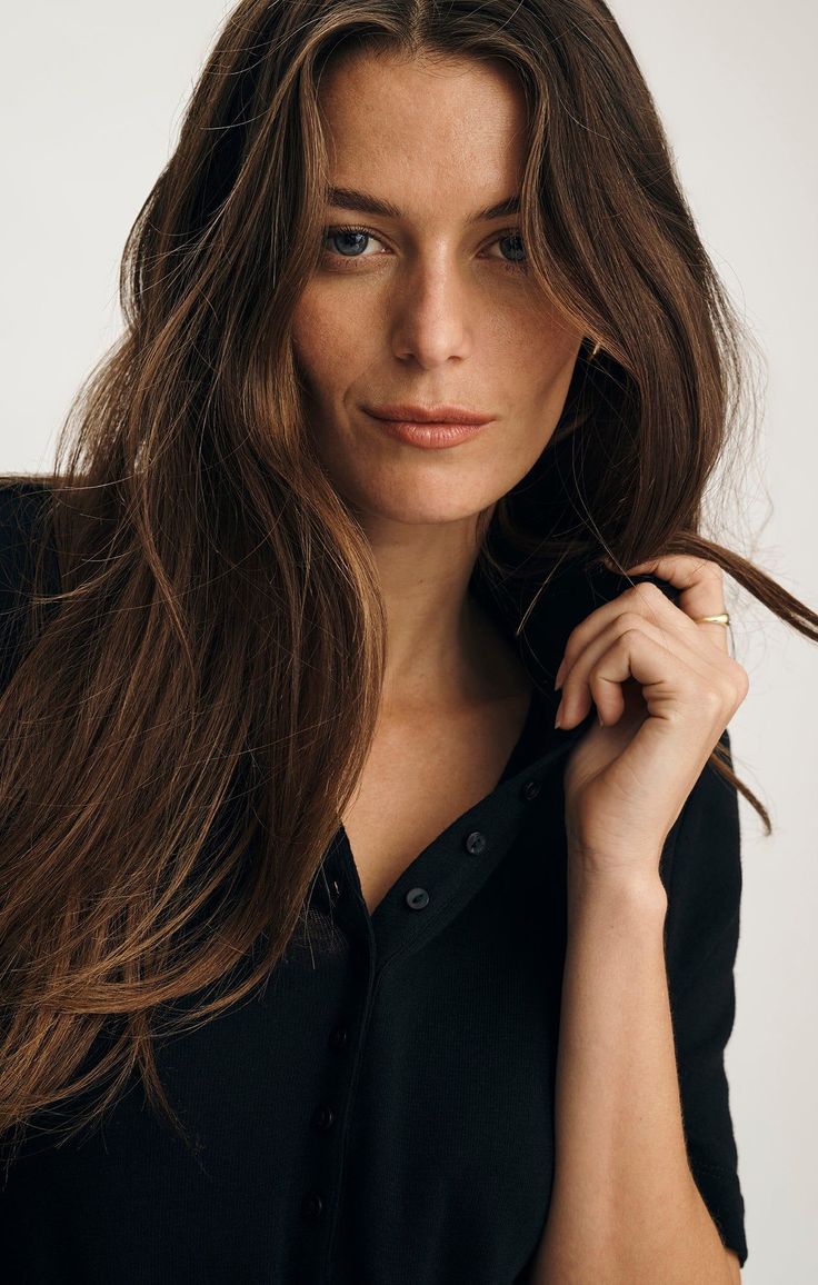 Woman with long brown hair and blue eyes wearing a black shirt