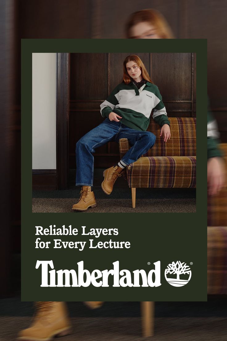 Woman with long red hair wearing a striped shirt, jeans, and boots, sitting indoors