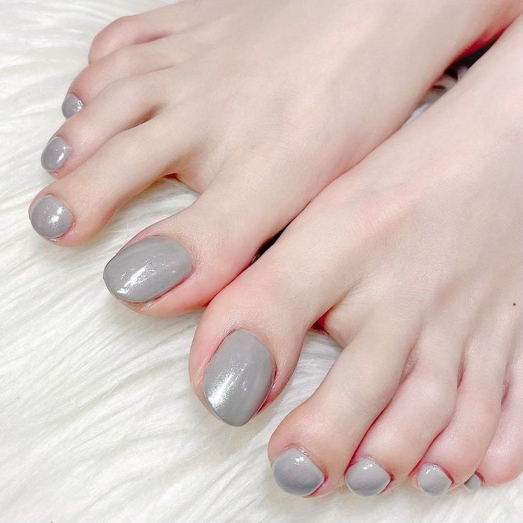 Close up of feet with gray nail polish on a white fur surface