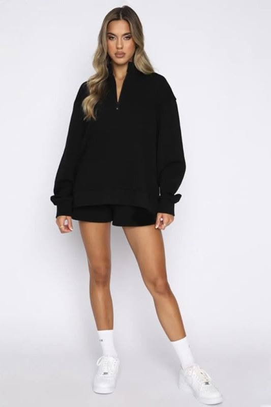 Woman in a black sweatshirt and shorts with white socks and sneakers