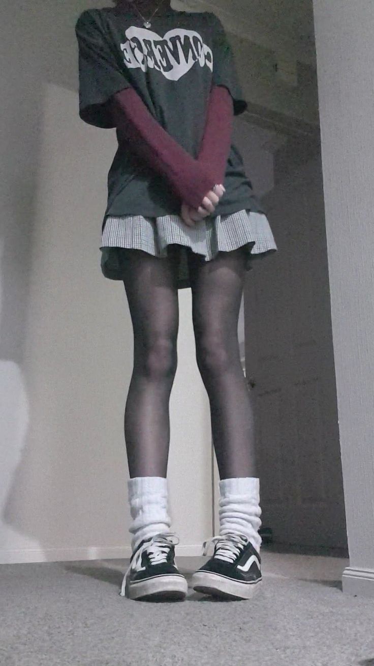 Person in a plaid skirt, black tights, and sneakers with an oversized t-shirt