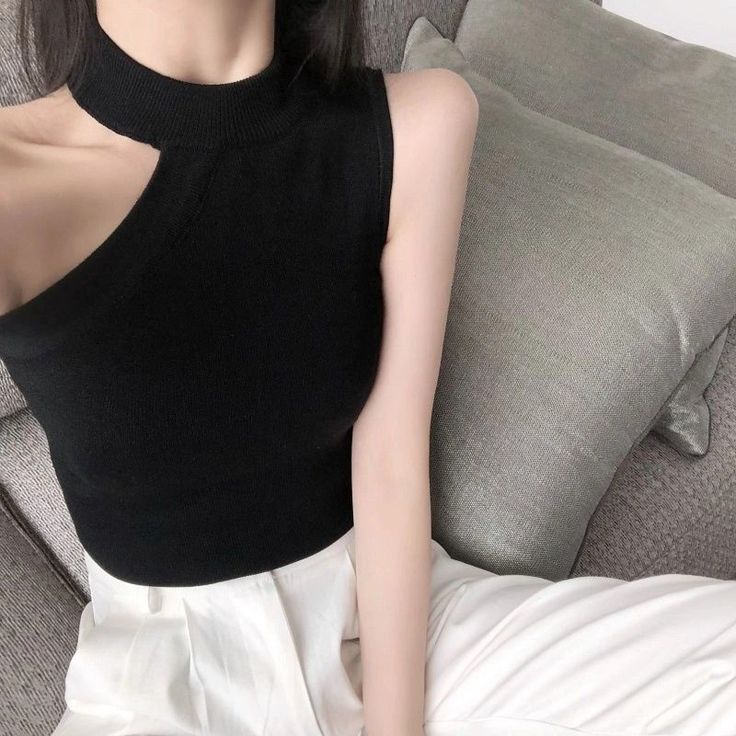 Person in a black cut-out top and white pants sitting on a couch