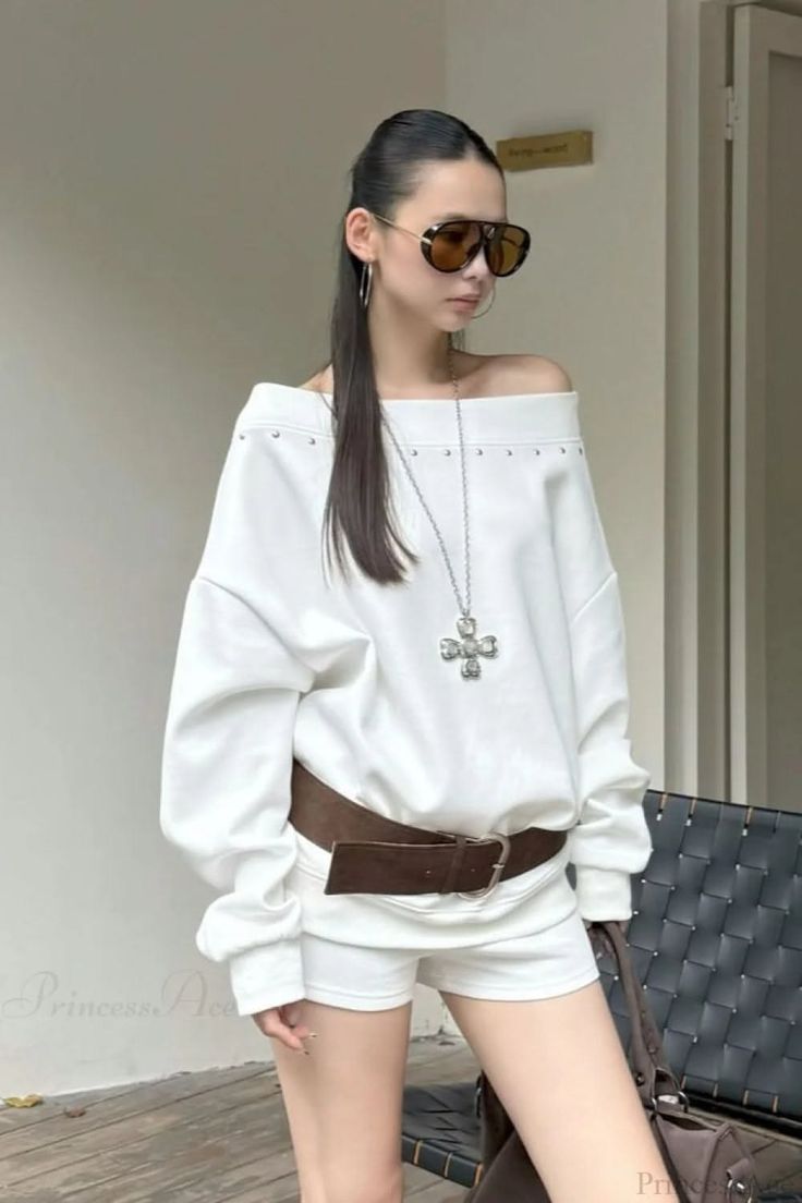 Woman in an off-shoulder top, white shorts, and sunglasses outdoors