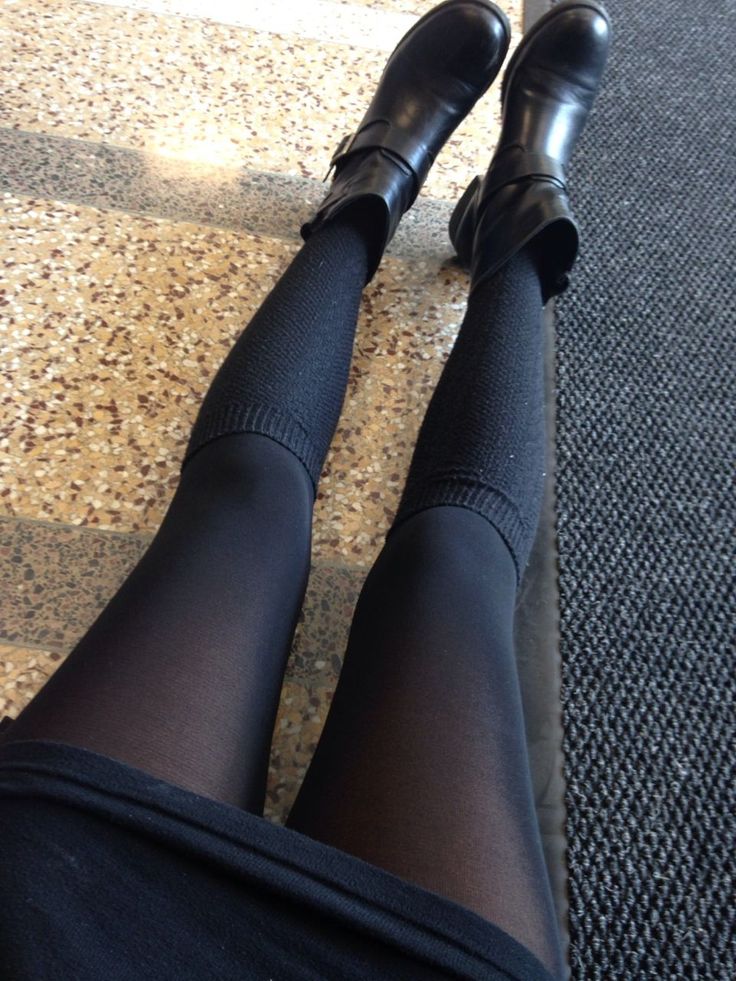 Person wearing black boots and tights, sitting indoors