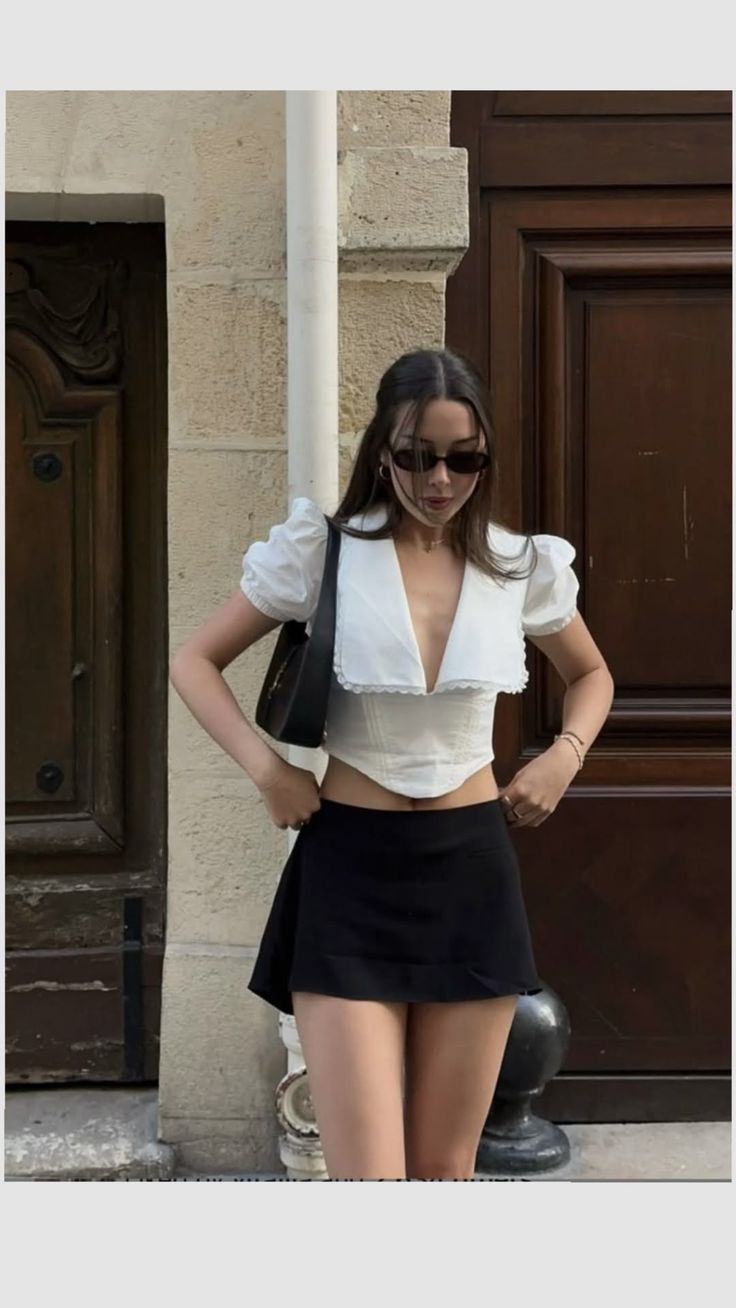 Woman in a white crop top and black mini skirt posing outdoors